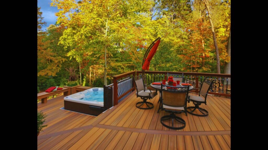 An outdoor wooden deck featuring a dining table set, sectional seating, and bright green trees in the background.