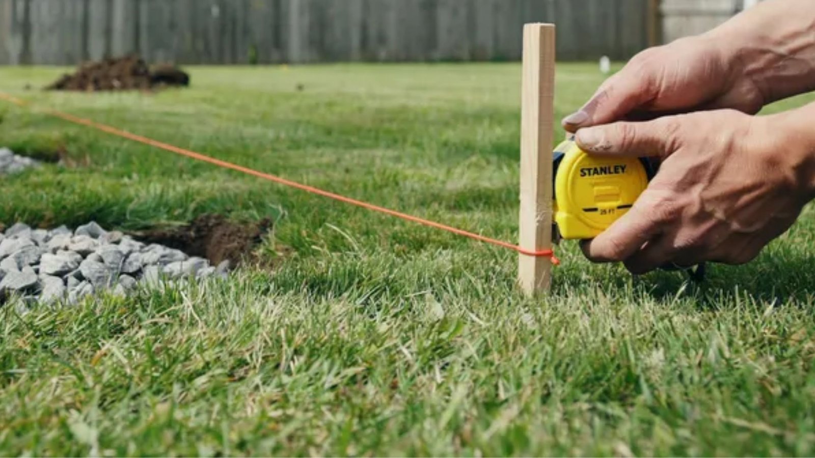 measuring and marking the layout for DIY shade sail post installation.
