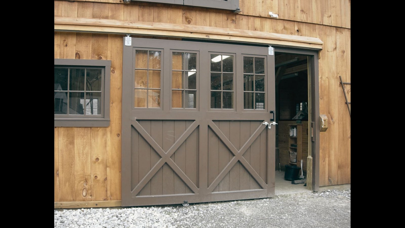 Sliding double shed doors with upper glass window panels mounted on an outdoor wooden shed.