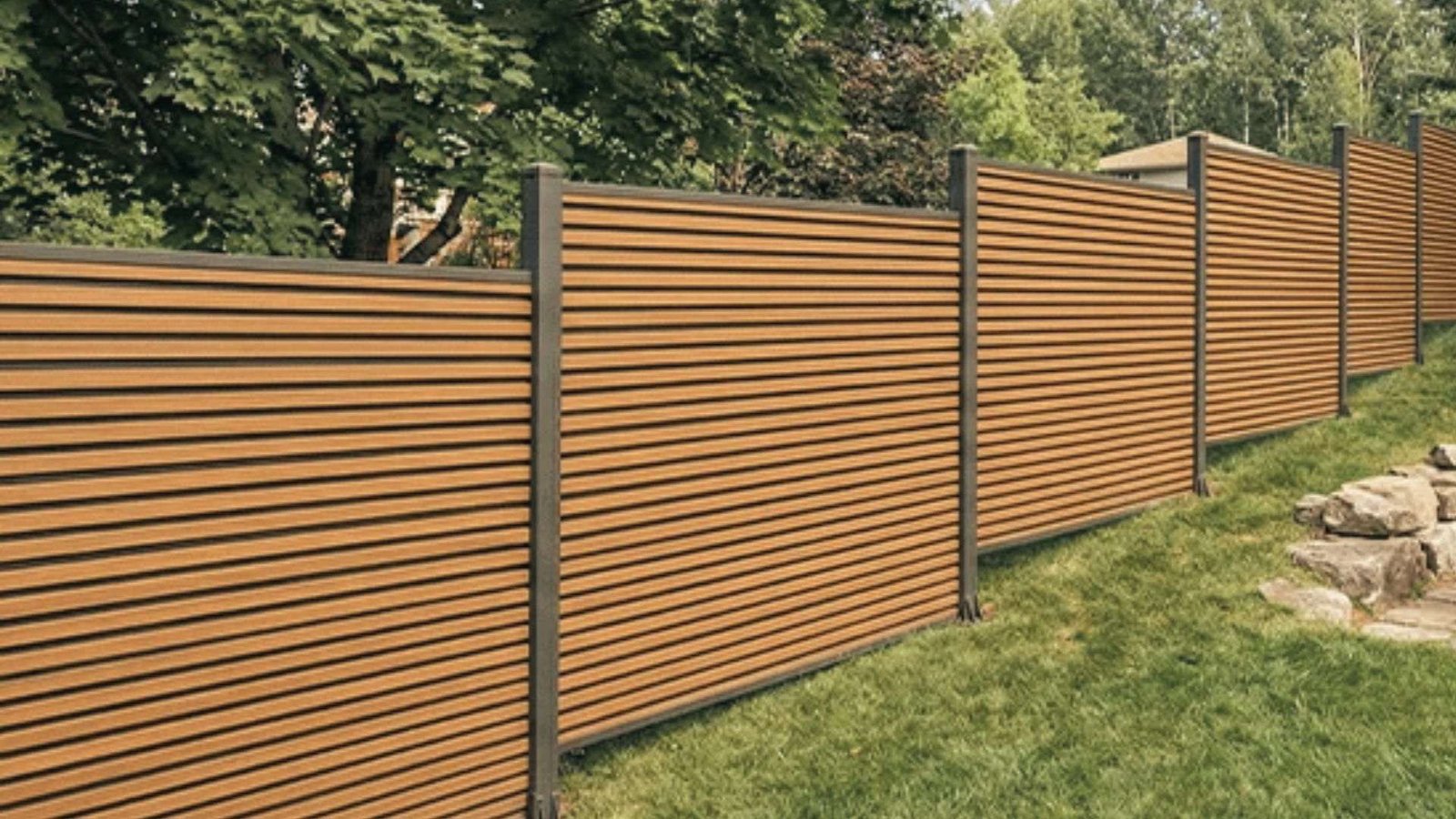 Modern composite horizontal slat fence stepping down a sloped grassy yard with posts