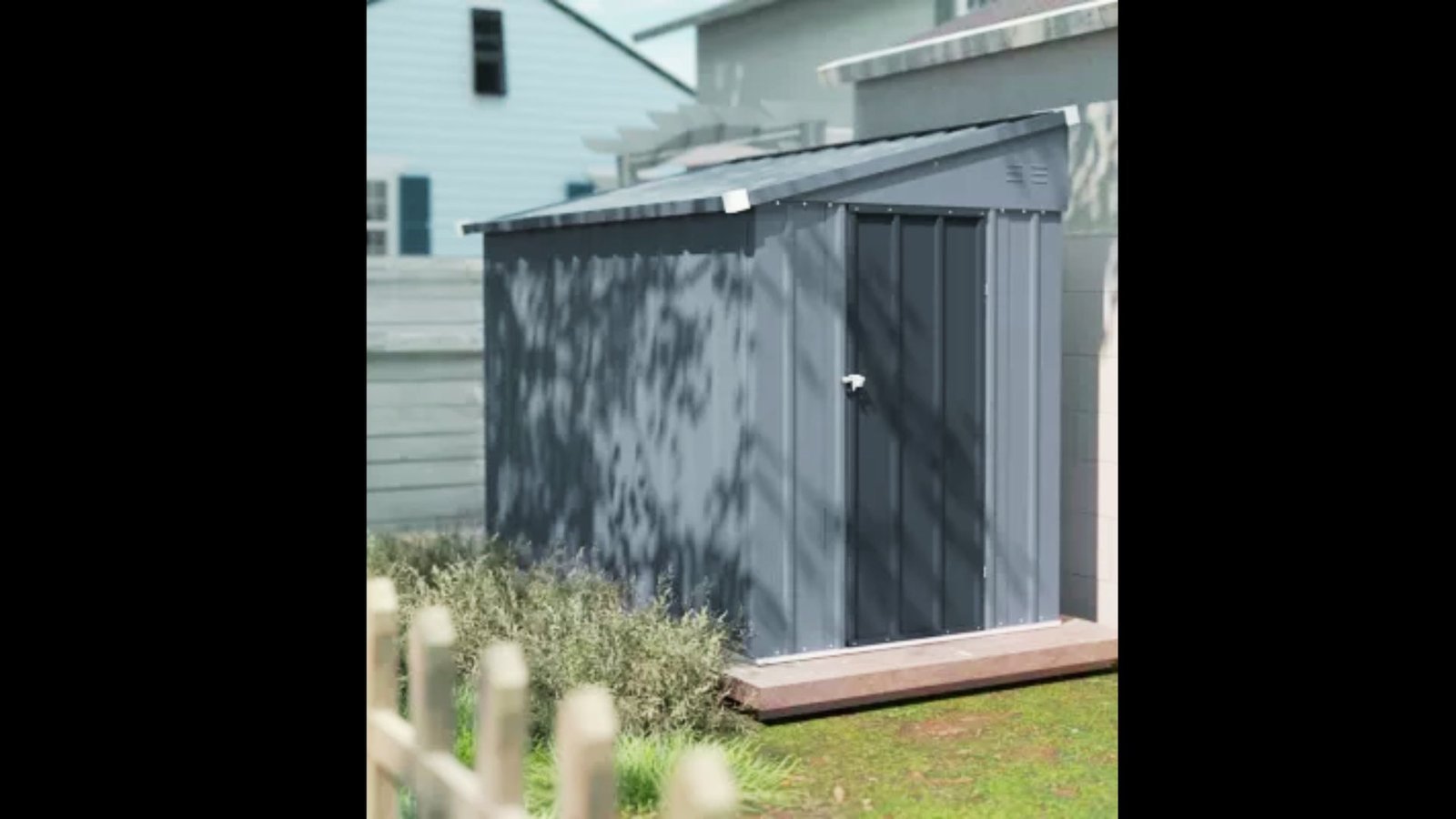 A small grey metal utility shed with corrugated roofing and double doors in a backyard setting.