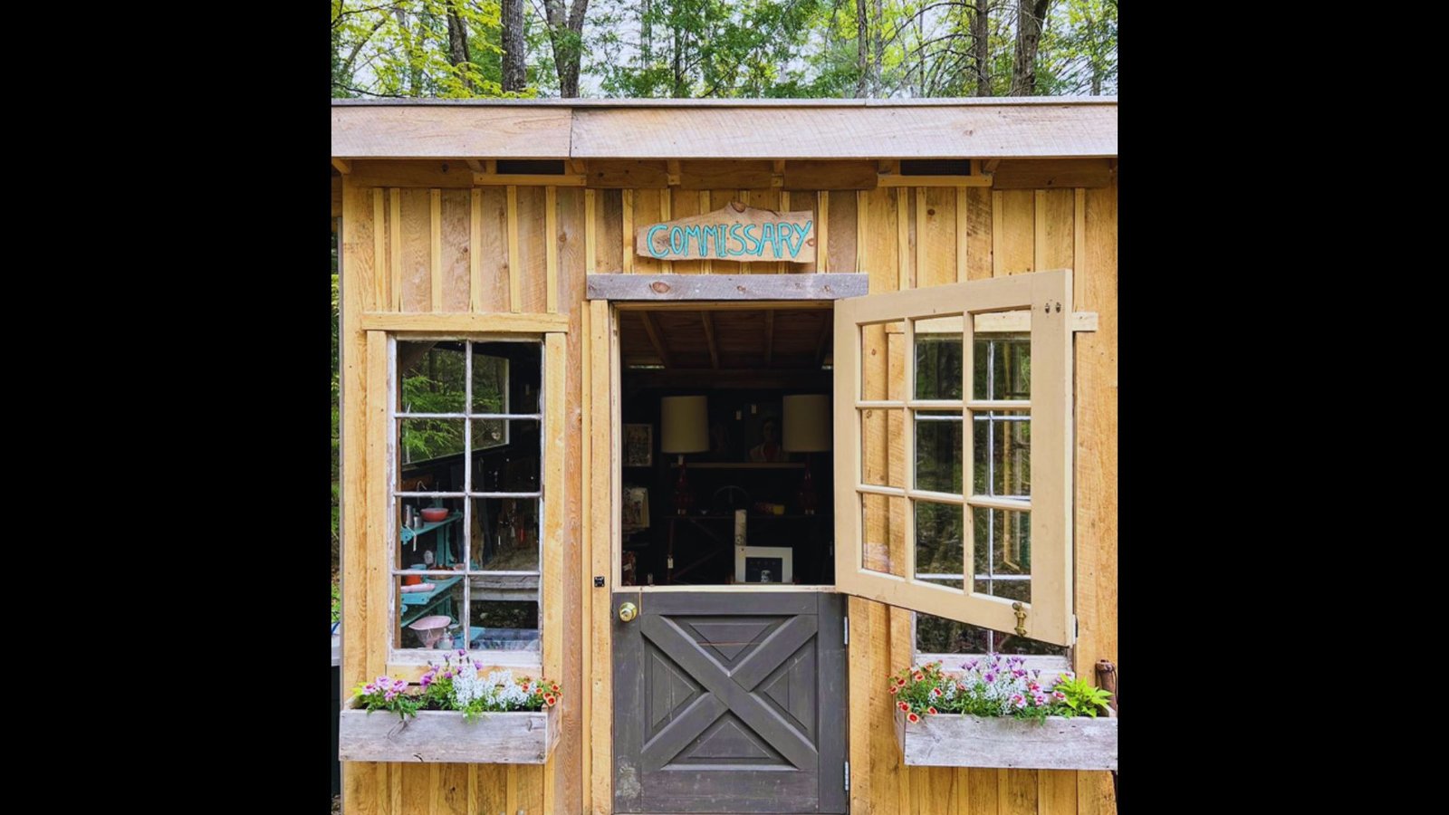 Wooden garden shed displaying a Dutch door with the top half opened to show the interior.