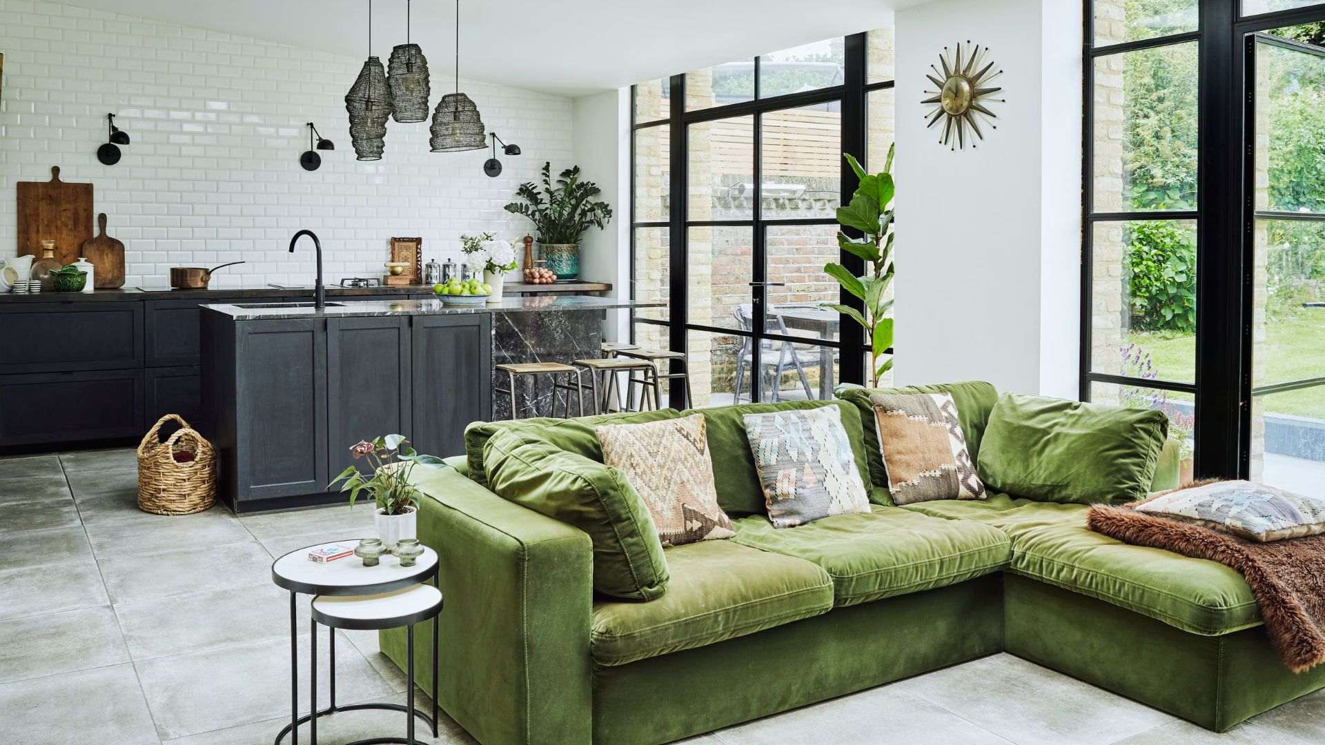 Open concept shed tiny house living kitchen layout - green velvet sectional, black cabinets and steel windows