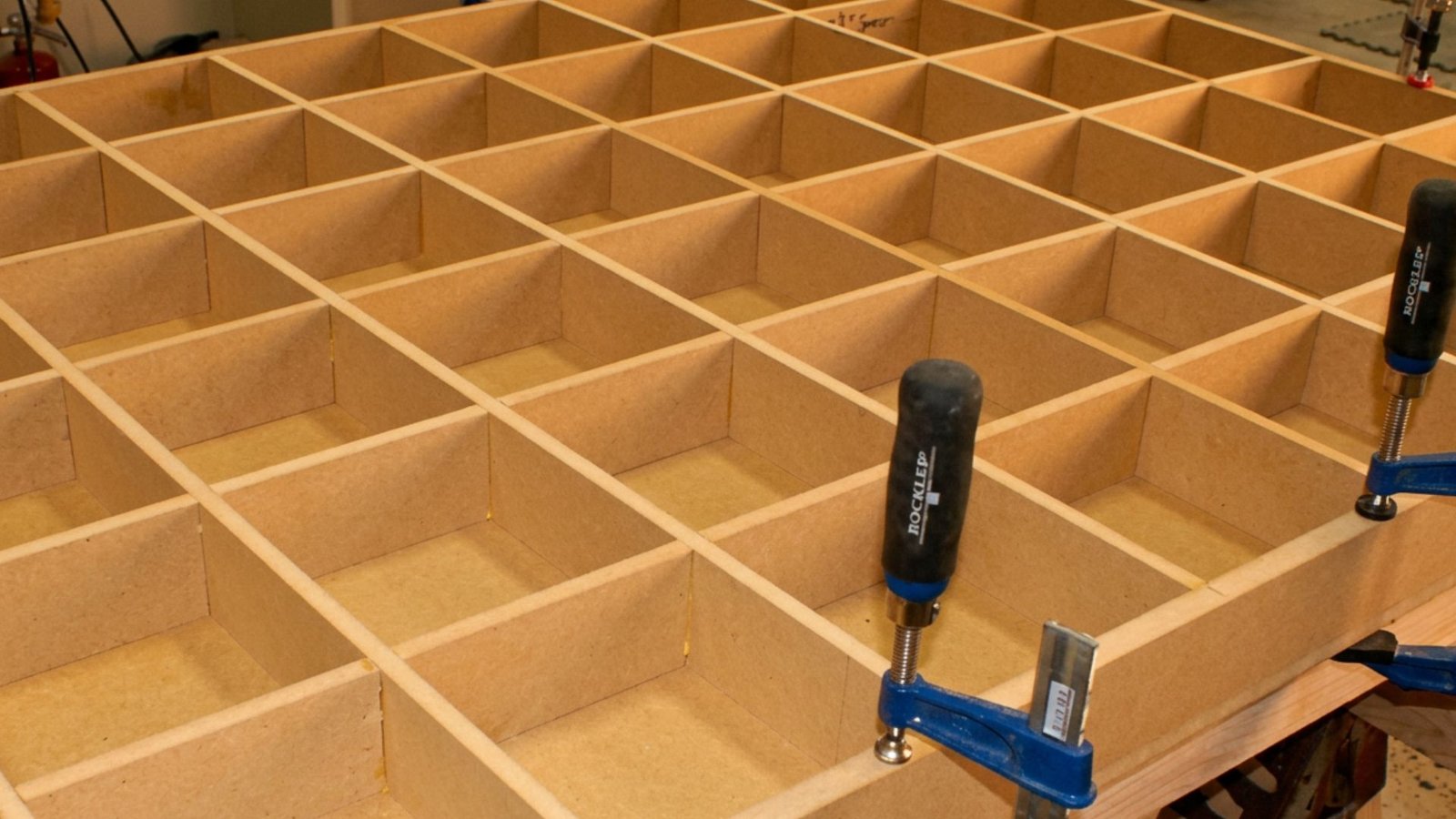 Torsion box grid of MDF ribs forming square cells, held together with blue clamps.