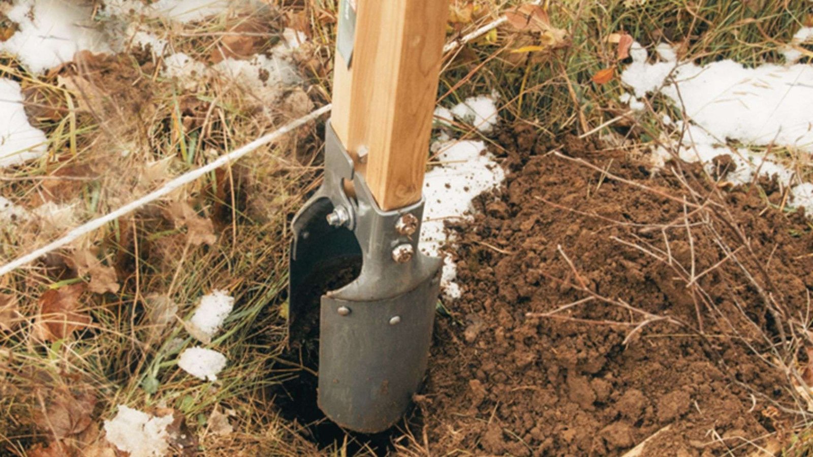 Digging fence post hole with post hole digger for step down fence on slope