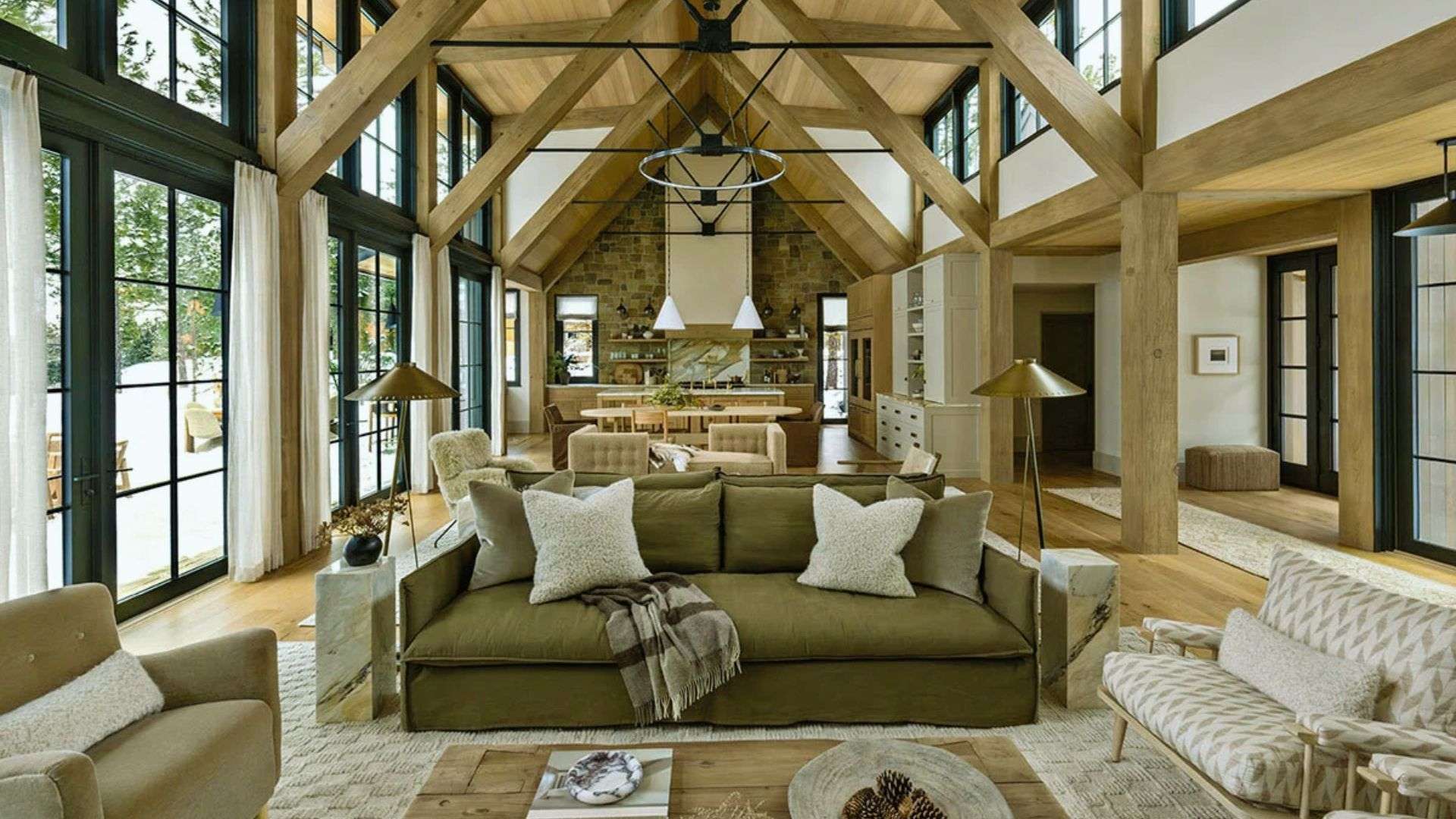 Modern farmhouse shed tiny house with warm wood finishes - vaulted timber beams, stone wall and olive sofa