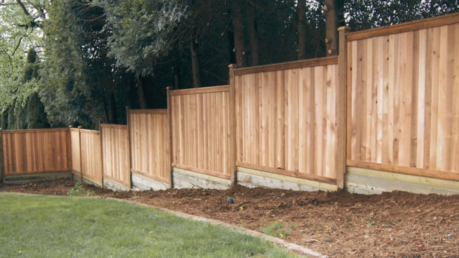 Wooden privacy fence stepping down a sloped yard using step down method