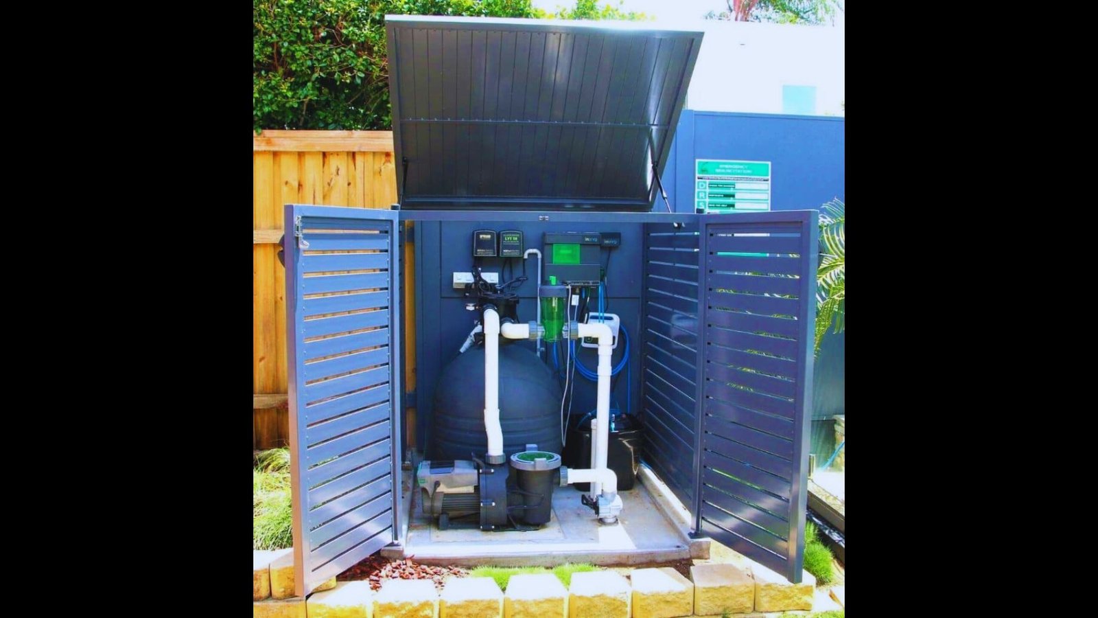 Blue outdoor composite equipment storage box with raised lid and open doors showing pool filter system inside.