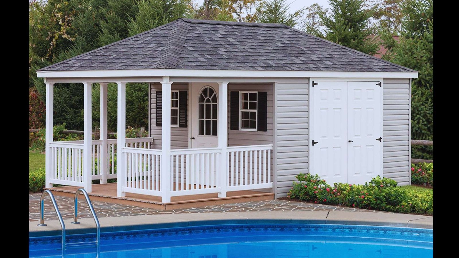 A white cottage-style pool shed with a screened porch and dark shingled roof positioned beside a swimming pool.