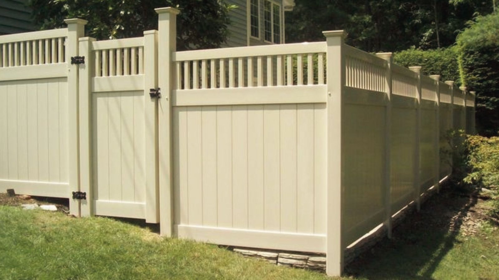 Vinyl stepped fence with gate installed on sloped backyard