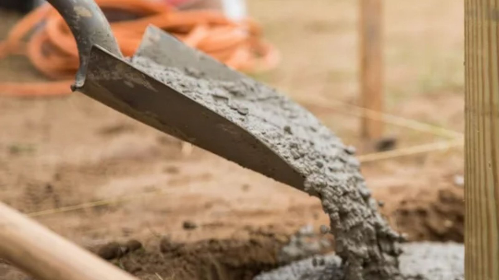 concrete being poured around a wooden shade sail post for a strong footing.