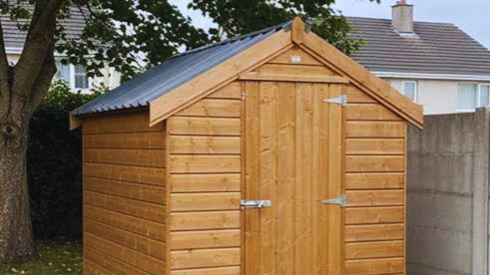 Alt text: Wooden garden shed with a gable roof, dark corrugated metal sheeting, and double doors, standing in a back garden.