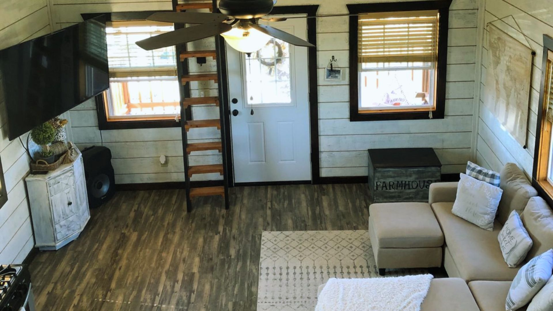 Shed tiny house living room maximizing comfort - sectional sofa, loft ladder, shiplap walls and natural light design