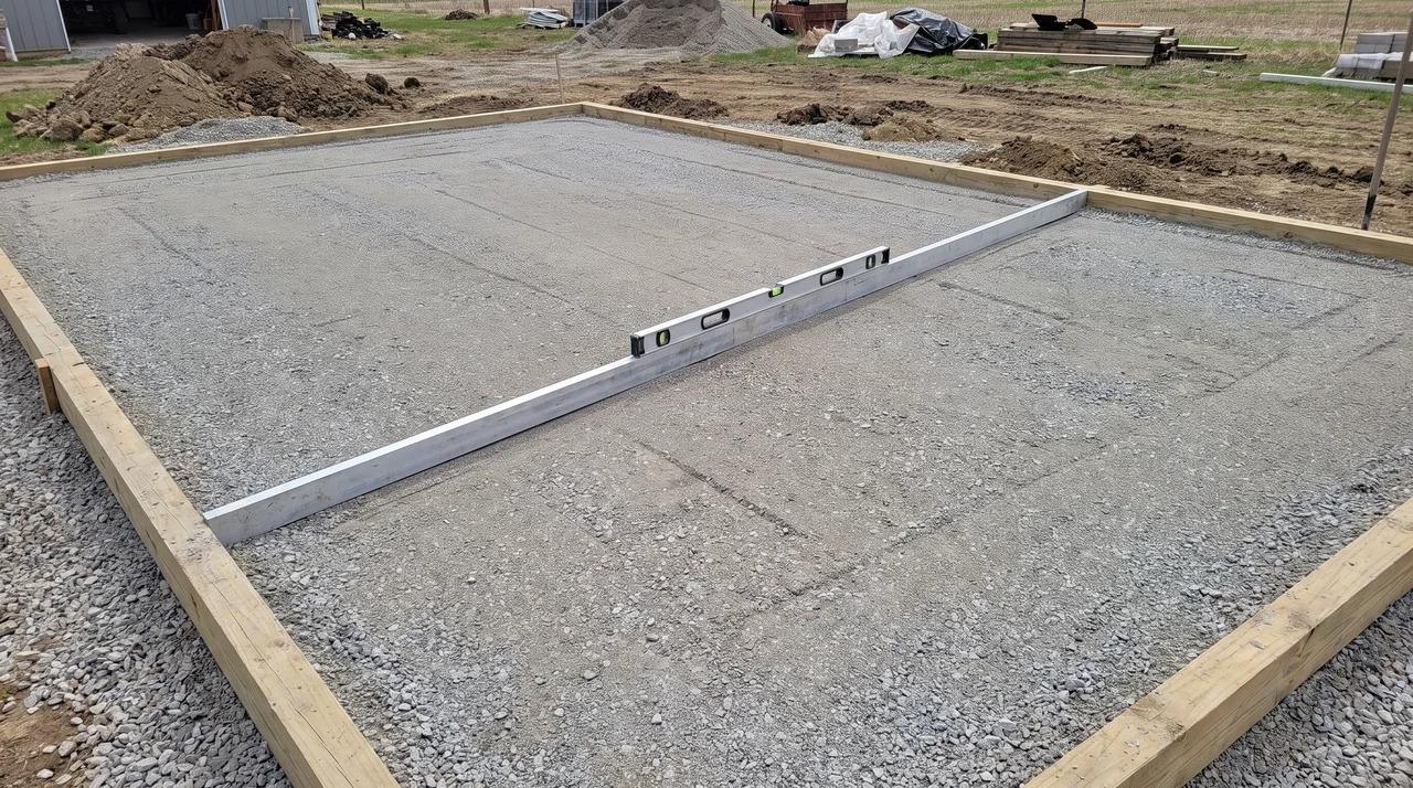 Level and straightedge checking a completed gravel shed foundation