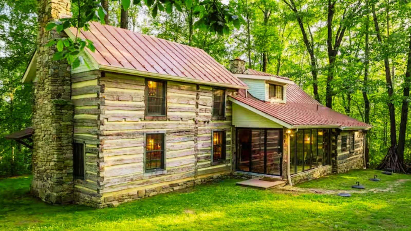 A charming log cabin surrounded by lush greenery in a tranquil woodland area.