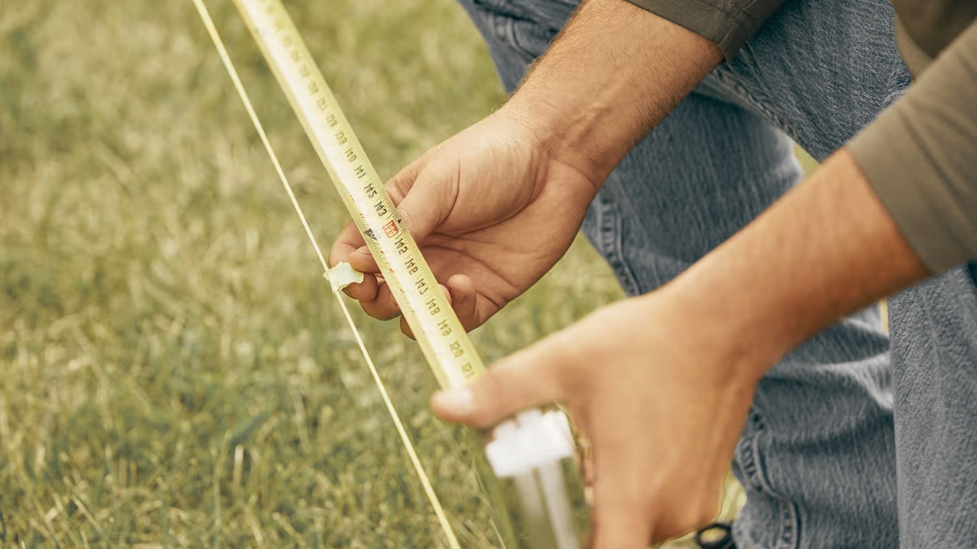 Measuring property line with tape and string for step down fence installation