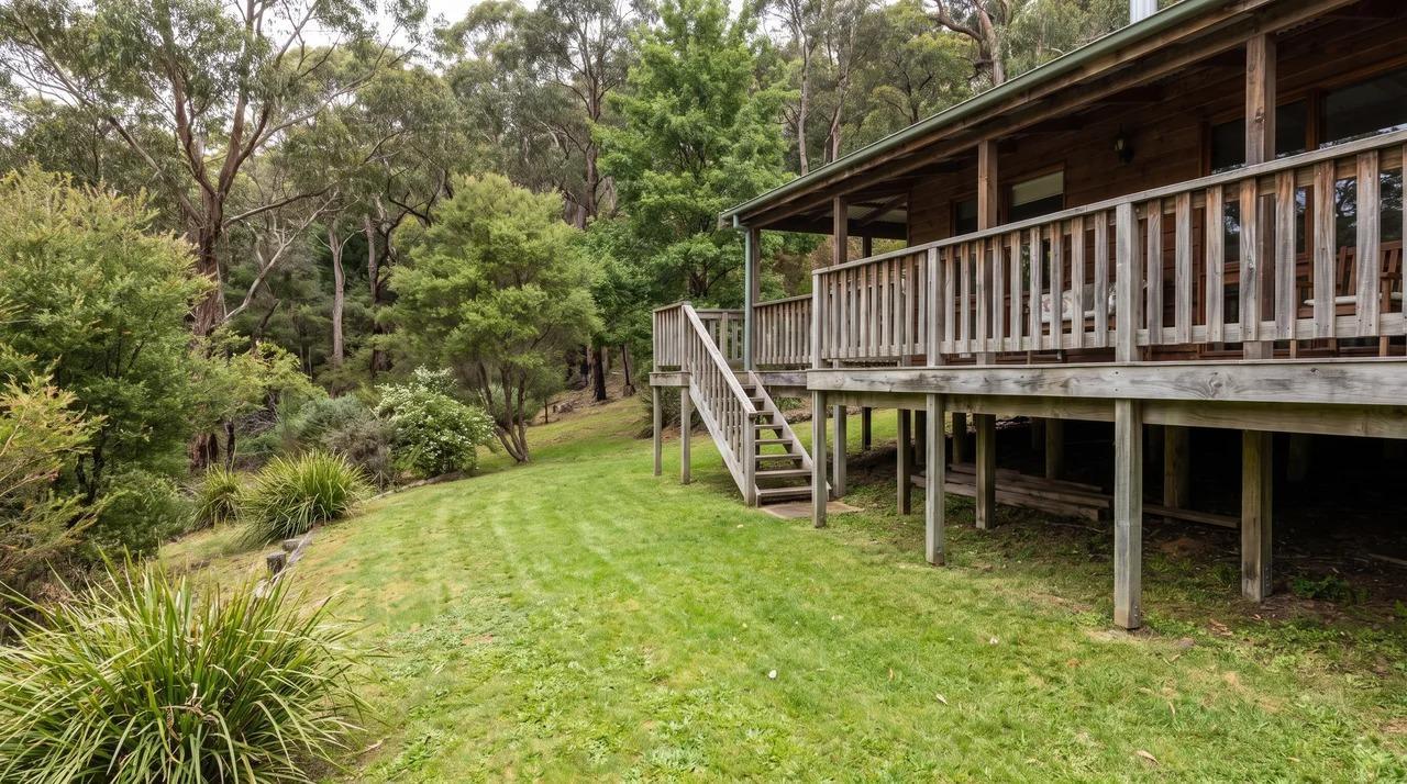 Elevated wooden deck on posts with stairs leading to a green lawn