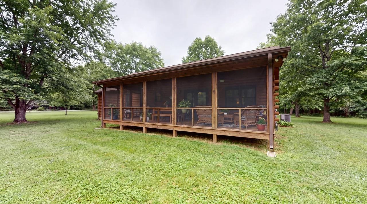 Screened-in deck porch surrounded by a grassy lawn and trees