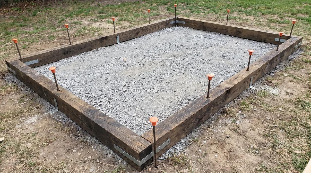 Pressure-treated timber frame anchored around a shed foundation