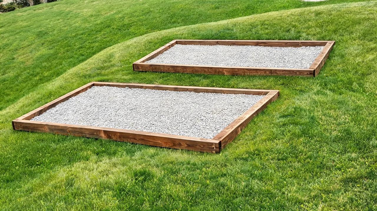 Stepped gravel pad held by landscape timbers on a gentle slope