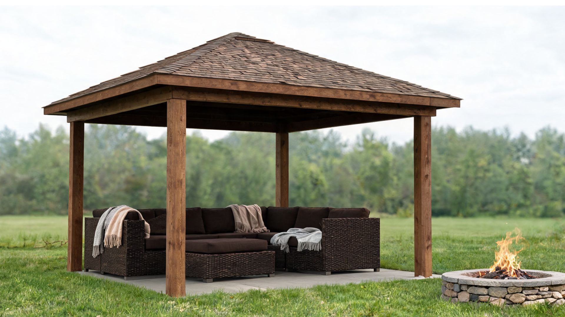 Small cabana with solid roof and open sides, deep seating with throw blankets, and a fire pit set away from the posts